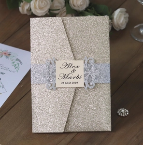 Détail d'invitation de mariage découpée au laser avec paillettes dorées et ruban argenté