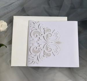 Detail of laser-cut white wedding invitation with elegant vine patterns and matching envelope