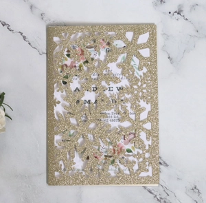 Macro detail of laser-cut gold glitter snowflake wedding invitation card on marble
