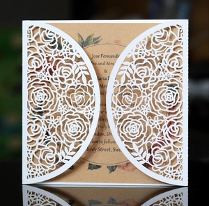 Detail of laser-cut rose hollow pattern on white wedding invitation with kraft paper inner