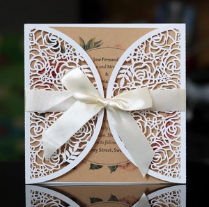 Intricate laser-cut white rose wedding invitation with vintage floral inner card and ribbon