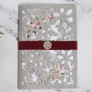 Elegant laser cut snowflake holiday invitation with burgundy ribbon and crystal buckle