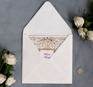 Detailed laser-cut wedding invitation card with elegant cream insert and floral lace texture