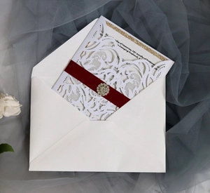 Détail d'invitation découpée au laser avec ruban rouge et boucle en strass brillant