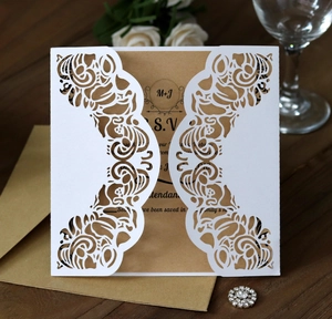Detailed laser-cut floral wedding invitation set with kraft paper inserts on wood