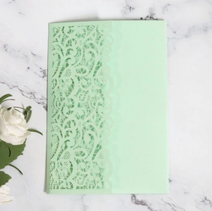 Detail of laser-cut lace floral pattern on light green premium wedding invitation card