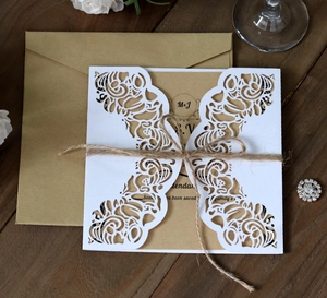 Detail of laser-cut floral wedding invitation with kraft paper and rustic twine bow