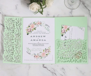 Detail of mint green laser-cut wedding invitation set with floral card on marble surface