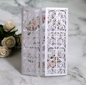 Elegant laser cut floral wedding invitation with vintage inner card on marble background