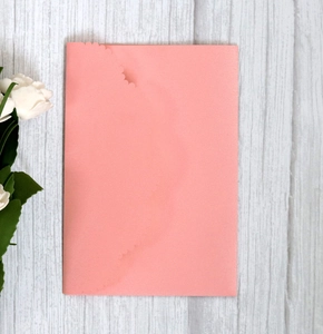 Detail of pink wedding invitation card with elegant scalloped edges on wood background