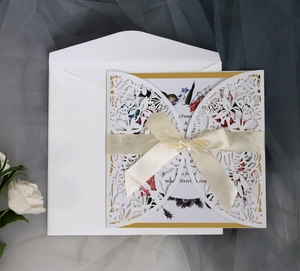 Elegant laser-cut wedding invitation with white ribbon and gold-bordered inner card
