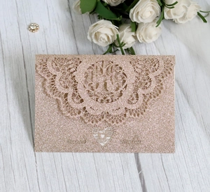 Macro shot of glittery rose gold wedding invitation with laser cut lace and heart detail