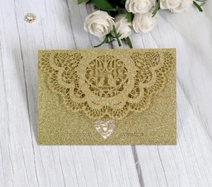 Detail of laser-cut glitter gold wedding invitation with intricate floral hollow patterns