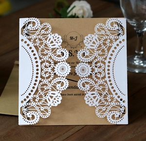 Detailed view of laser-cut wedding invitation with kraft paper inserts on a wooden table