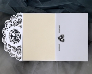 Elegant white laser-cut lace wedding invitation with a beige inner card and heart pattern