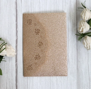 Detail of rose gold glitter wedding invitation featuring intricate laser-cut floral patterns