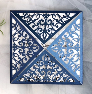Macro detail of laser-cut floral patterns on dark blue paper with white wedding insert