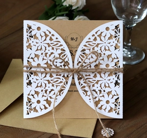 Detail of laser-cut floral wedding invitation with kraft paper, twine, and rhinestone pendant