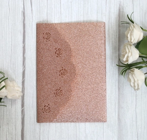 Macro detail of laser cut glitter paper rose gold wedding invitation with floral patterns