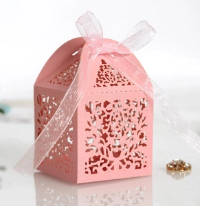 Pink laser-cut wedding favor box with elegant hollow flower patterns and ribbon