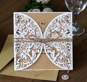 Close-up of laser-cut wedding invitation with butterfly patterns and kraft paper inlay