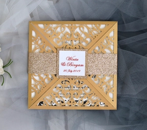 Detail of laser-cut gold wedding invitation with glitter belly band and custom label