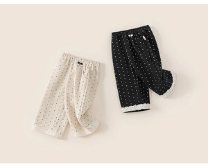 Close-up of girls polka dot trousers with elastic waist, bow, and white lace trim detail