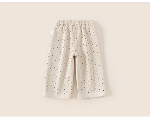 Detail of girls' beige polka dot pants with elastic waist and white lace trim hem