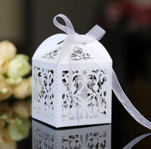 White laser-cut lace candy box with silk ribbon and elegant floral pattern for wedding favors