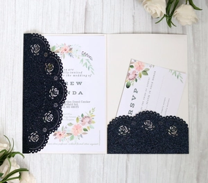 Detailed laser-cut rose lace wedding invitation set in navy blue glitter finish on wood