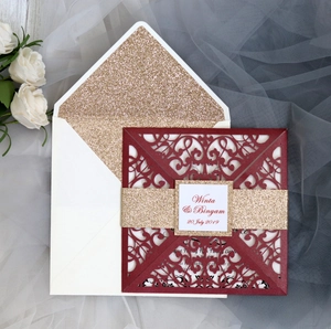 Macro detail of burgundy laser cut wedding invitation with gold glitter belly band and envelope
