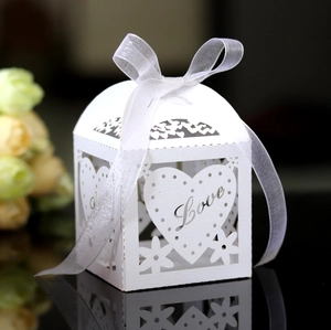 Macro view of white laser-cut wedding favor box with Love heart pattern and ribbon