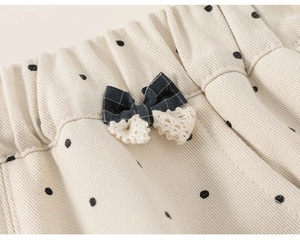 Close-up of elastic waist with polka dots, fabric bow and lace trim on girl's pants