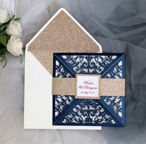 Macro detail of laser-cut navy wedding invitation set with gold glitter belt and envelope