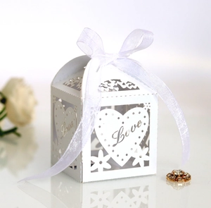 Macro detail of white laser-cut hollow candy box with Love text and organza ribbon