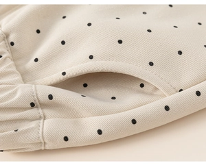 Detailed view of polka dot kid's trousers showing elastic waistband and side pocket texture
