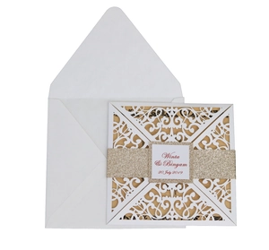 Detail of laser-cut wedding invitation with white floral lace pattern and gold glitter band