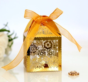 Elegant gold laser-cut floral wedding favor box with a delicate orange chiffon ribbon bow