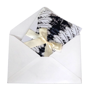 Elegant laser cut white wedding invitation with black floral insert and cream satin ribbon