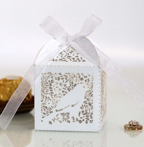 Detailed laser-cut white wedding favor box with bird patterns and white ribbon bow