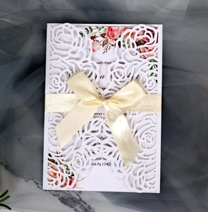 Close-up of laser-cut rose floral wedding invitation with red floral print and silk bow