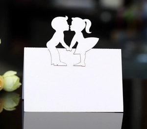 Close-up of laser-cut wedding place card with boy and girl silhouette in white cardstock