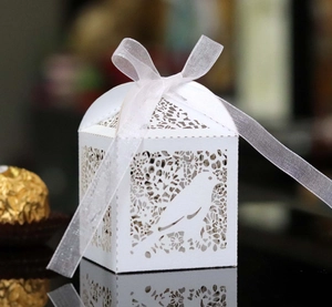 Detailed laser-cut white favor box featuring elegant bird motifs and a white ribbon bow