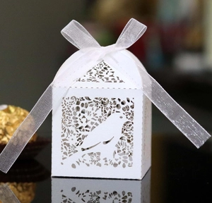 Detailed laser-cut candy box with bird and flower patterns and a white silk ribbon