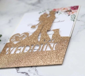 Close-up of glitter gold laser cut wedding cake topper with couple and dog silhouette