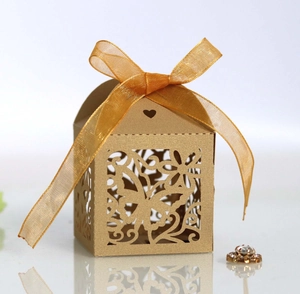 Macro view of gold laser-cut butterfly wedding candy box with heart detail and ribbon