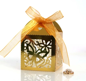 Detailed laser-cut golden butterfly wedding favor box with a satin bow and hollow design