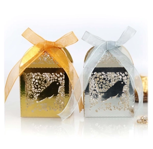 Detail view of laser-cut wedding favor boxes with bird patterns and organza ribbons