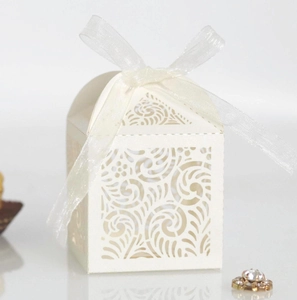 Detail showing laser-cut floral pattern on white wedding favor box with ribbon