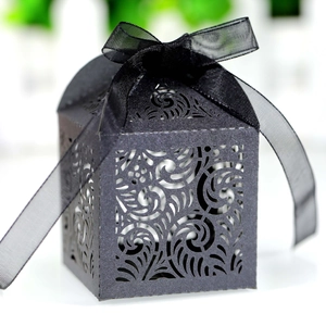 Close-up of black laser-cut wedding favor box with shimmering paper and chiffon ribbon